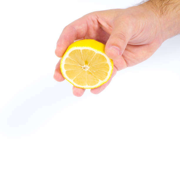 istock Males hand holding a half lemon and squeeze it with white background 835423528