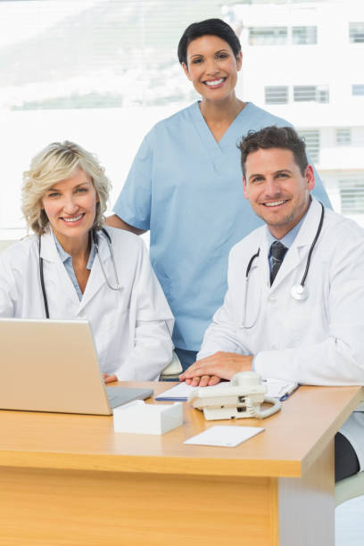 istock Smiling doctors with laptop at medical office 835430158