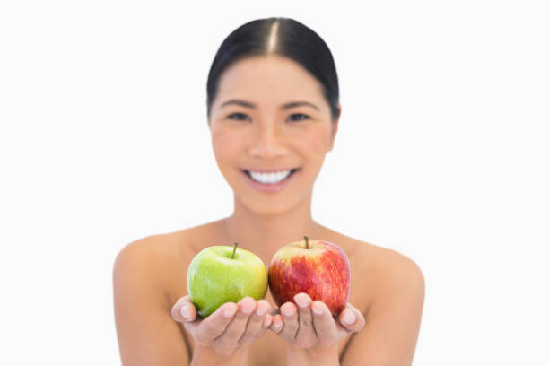fröhlich natürlichen brunette holding roten und grünen äpfeln - sensuality women apple naked stock-fotos und bilder