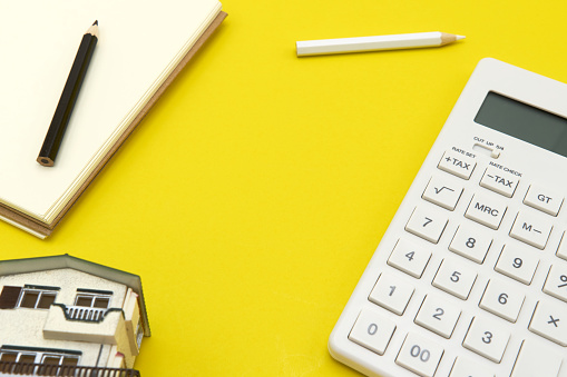 The concept of working desk layouts. The background is yellow with a calculator, a pencil, a white pencil and a black house simulator. copy space.