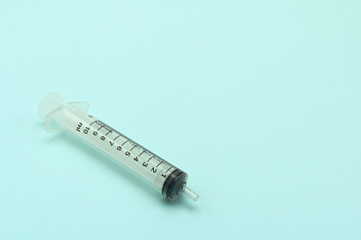 Plastic syringe without needle for liquid suction Lay on a blue-green background. copy space.