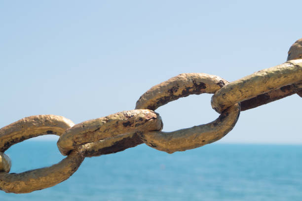istock Old metal chain painted with gold paint on beach background in the sunlight 835447622