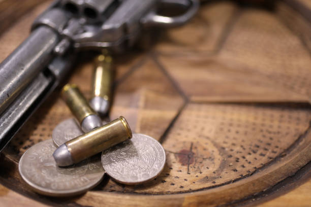 Old western Six Shooter with bullets and old American and Mexican coins.  Table has a TEXAS star carved into the wood.