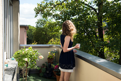 The background picture was taken at home on a balcony, where the woman is relaxing, while she is having a cup of tea.