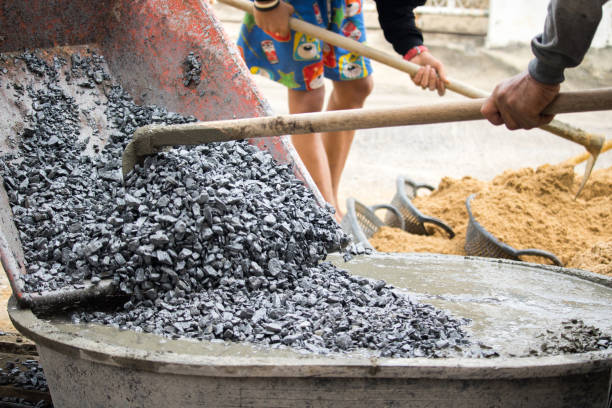 istock labor mixing cement and pebbles together for build new floor 835524806