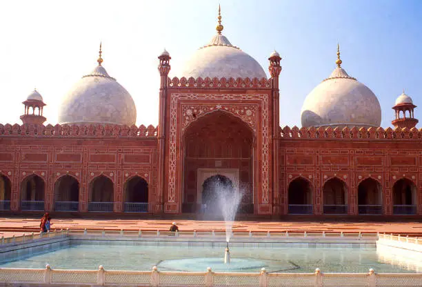 View across fountains in courtyard toward domes of Badshahi Mosque in Lahore Pakistan