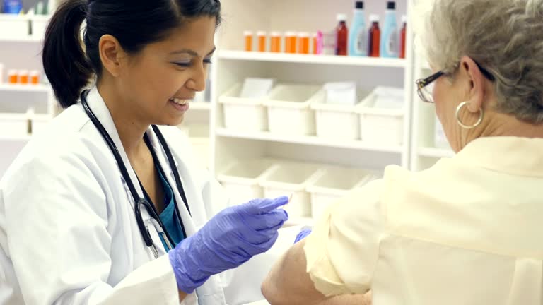 Asian pharmacist or doctor places bandage on senior woman after receiving flu vaccine
