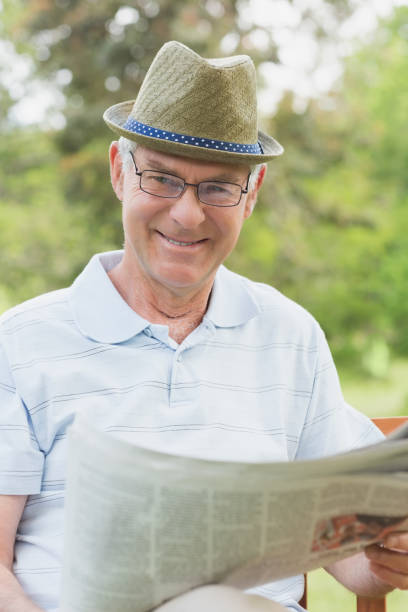istock Senior man reading newspaper at park 835626900