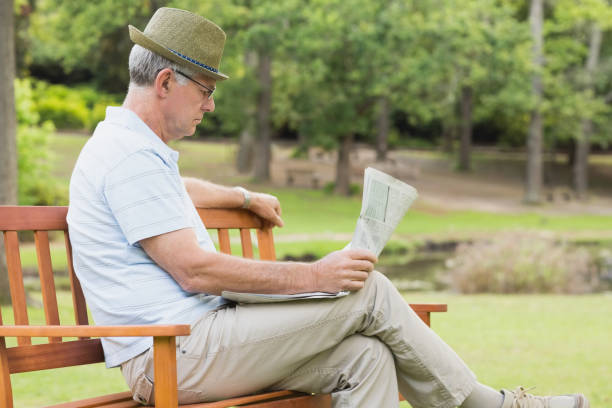 istock Relaxed senior man reading newspaper at the park 835627318