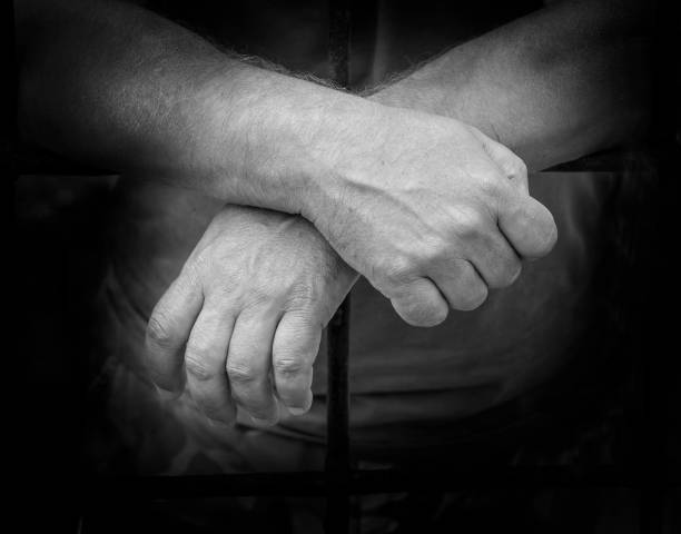 istock hands of a man behind bars prisons 835659760