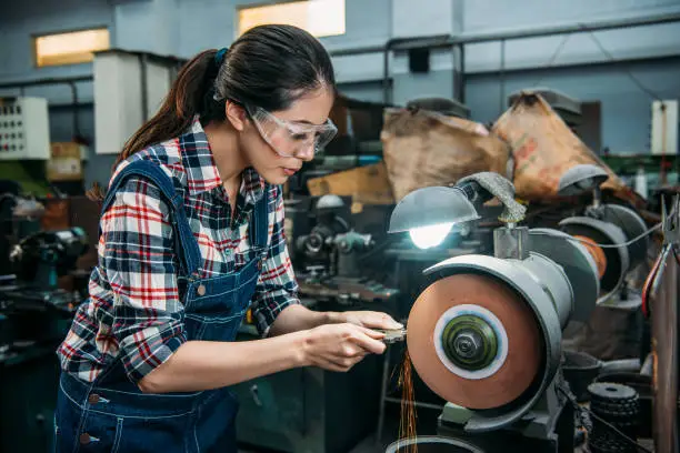 female worker holding components metal grinding