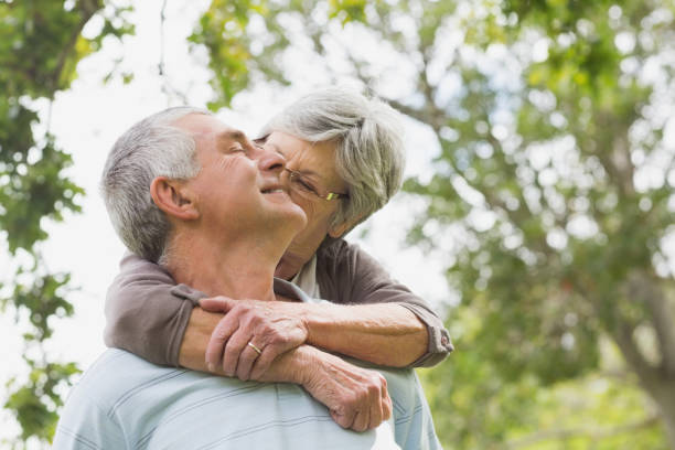 istock Senior woman embracing man from behind at park 835700940