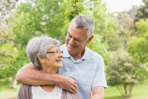 istock Senior man embracing woman from behind at park 835702976