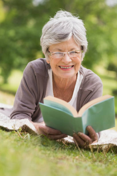 istock Senior woman reading a book at park 835703260