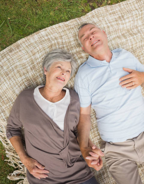 istock Smiling relaxed senior couple lying in park 835703438