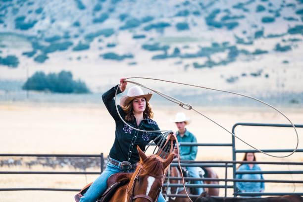 istock Young Cowgirl Lassoing Steer During Branding 835710512