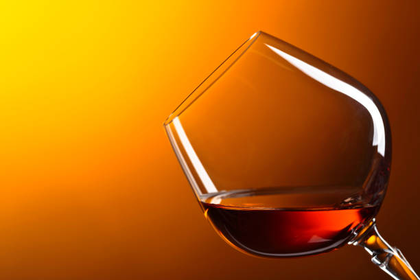 Snifter of brandy with copy space for text on a yellow background.