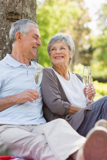 istock Happy senior couple with champagne at park 835732502