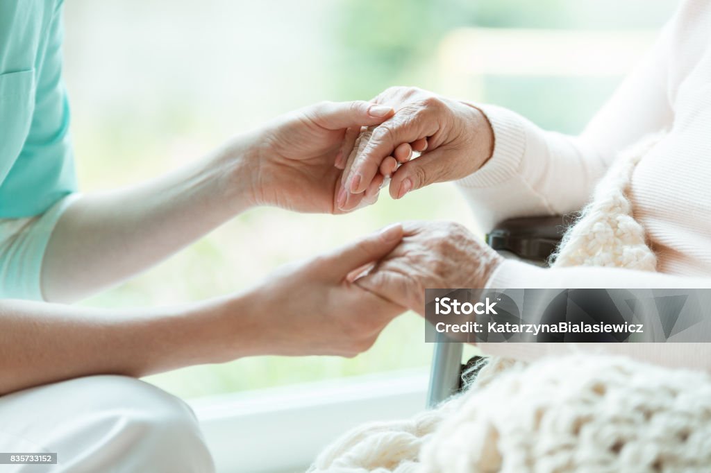 Nurse holding patient's hands Photo of nurse holding her woman patient's hands with painted nails Home Caregiver Stock Photo