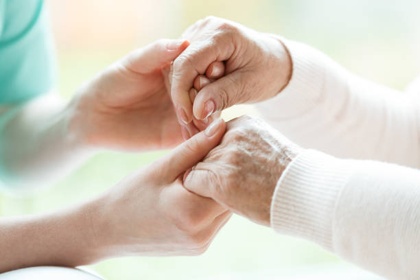 Close-up of holding hands Photo with close-up of caregiver and patient holding hands parkinsons disease photos stock pictures, royalty-free photos & images