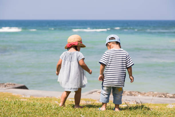 Twin brothers and sisters are having a good time with their mothers on the beach in Okinawa.