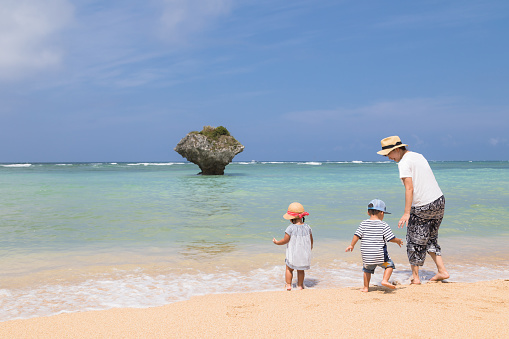 Twin brothers and sisters are having a good time with their mothers on the beach in Okinawa.