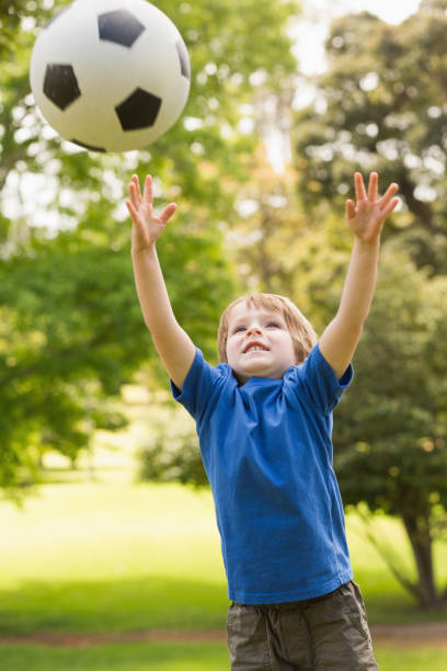 istock Smiling young boy playing with ball in park 835743526