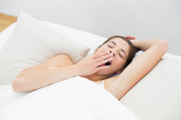 istock Woman yawning in bed with eyes closed 835743692