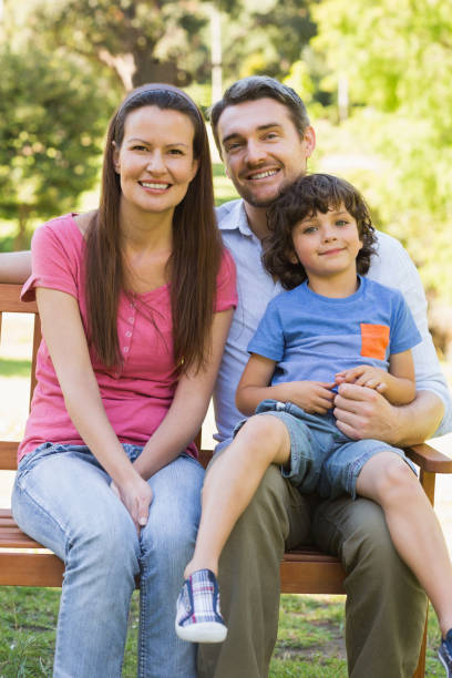 istock Smiling couple with son sitting on park bench 835754838