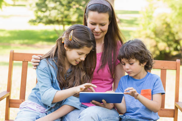 istock Woman with kids using digital tablet in park 835754896