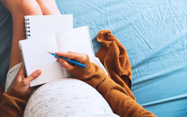 Pregnant woman makes notes and looking at medical documents. Pregnant woman makes notes and looking at medical documents. Concept of pregnancy, health care, gynecology, medicine. Mother waiting of baby. maternity dress stock pictures, royalty-free photos & images