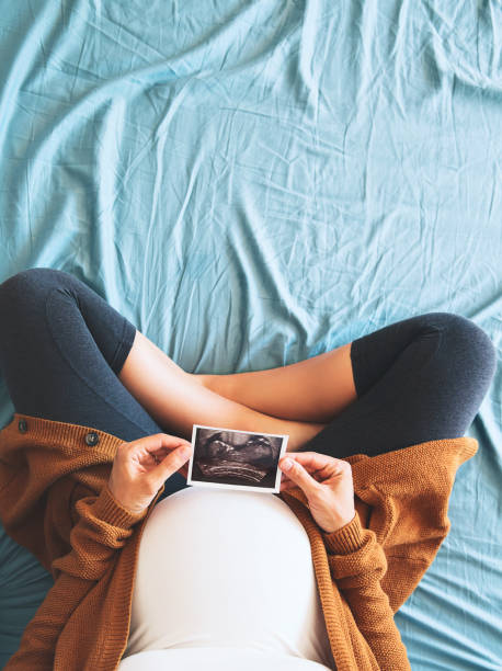 Pregnant woman holding ultrasound image. Pregnant woman holding ultrasound image. Concept of pregnancy, health care, gynecology, medicine. Young mother waiting of the baby. Close-up, copy space, indoors. technology office equipment laboratory stock pictures, royalty-free photos & images