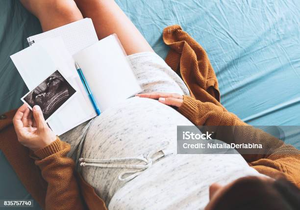 Mujer Embarazada Hace Notas Mirando La Imagen De Ultrasonido Y Documentos Médicos Foto de stock y más banco de imágenes de Feto - Etapa humana