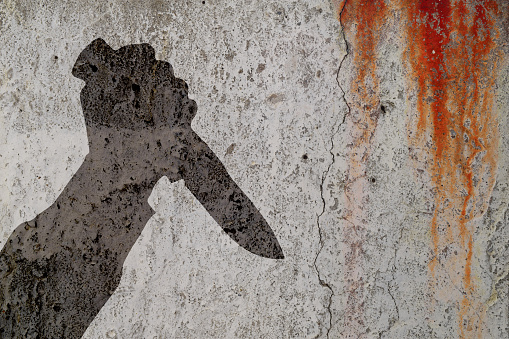 Human hand with killing knife silhouette in shadow on bloody cement wall background. Illustration for criminal news and chronicles.