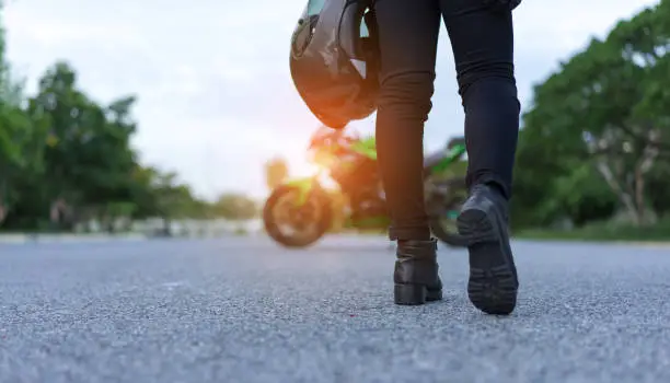 Photo of Young woman biker holding helmet equipment with jacket for safety protection when over high speed walking to motorcycle on street travel lifestyle.