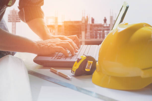 istock Architect engineer using laptop for working with yellow helmet, laptop and coffee cup on table. 835765316