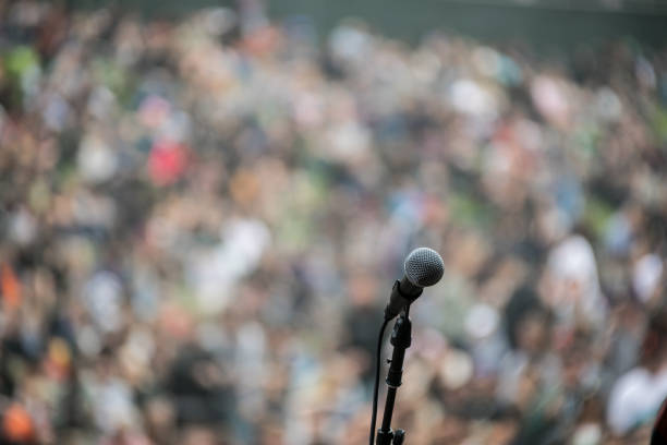 istock Close up of Microphone in front of crowd 835768870