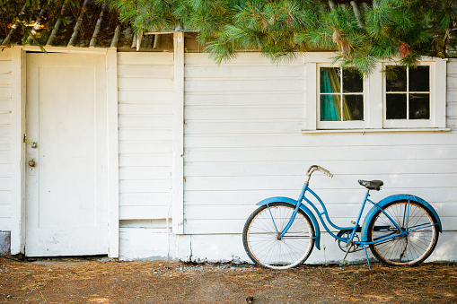 A blue bicycle in front of a white house in the countryside