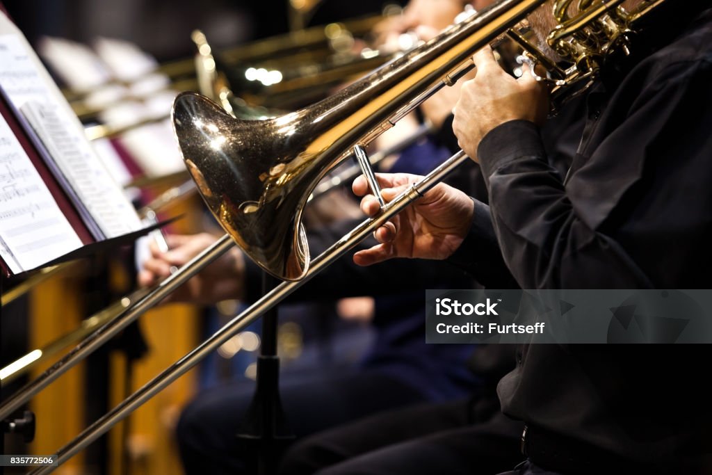 Trombones en las manos de músicos de la orquesta - Foto de stock de Trombón libre de derechos