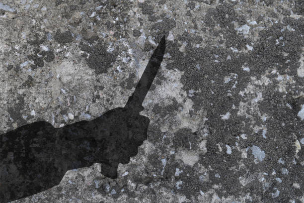 istock Shadow of human hand with killing knife on gray concrete wall 835779808