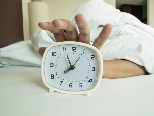 istock white alarm clock and sleeping man 835787386