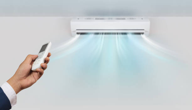 Hand with remote control directed and air conditioner stock photo