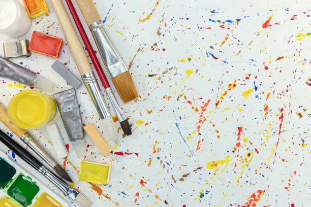 istock paintbrushes, watercolor and crayons on colorful paint blobs background 835810366