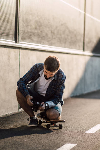 istock Hipster sits on a skateboard and holds the camera 835820870