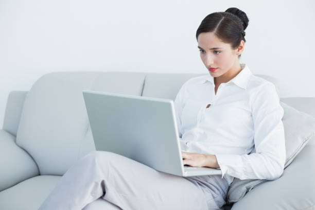 istock Well dressed woman using laptop on sofa 835824988