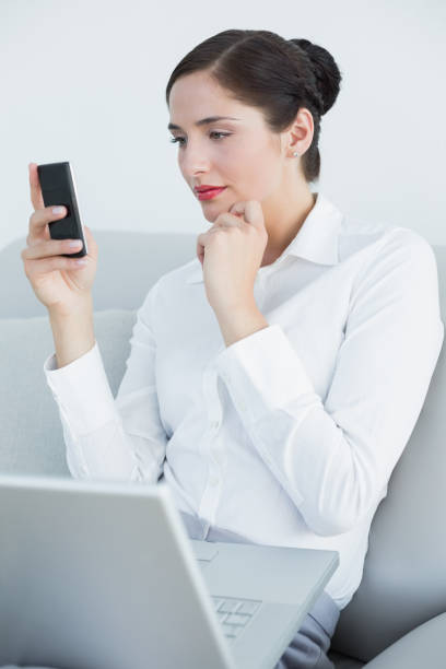 istock Well dressed woman using cellphone and laptop on sofa 835825288