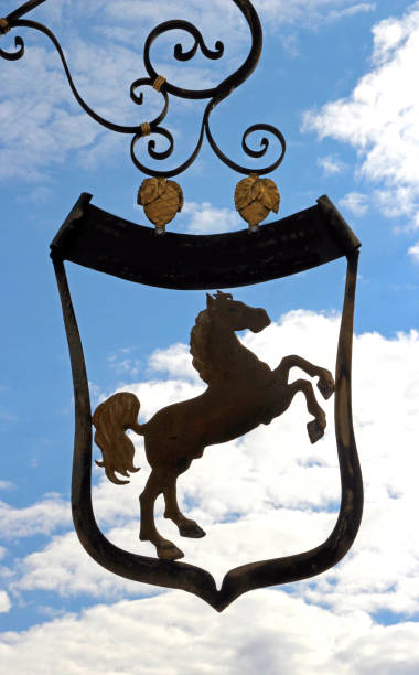 old inn sign with a horse in front of blue and white sky, shield,
