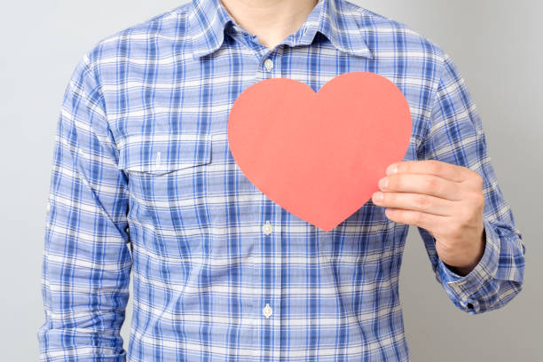 istock Man's hand holding red paper heart isolated on gray 835853140