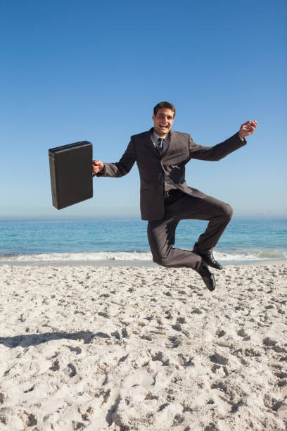 istock Cheerful businessman jumping on the beach 835853190