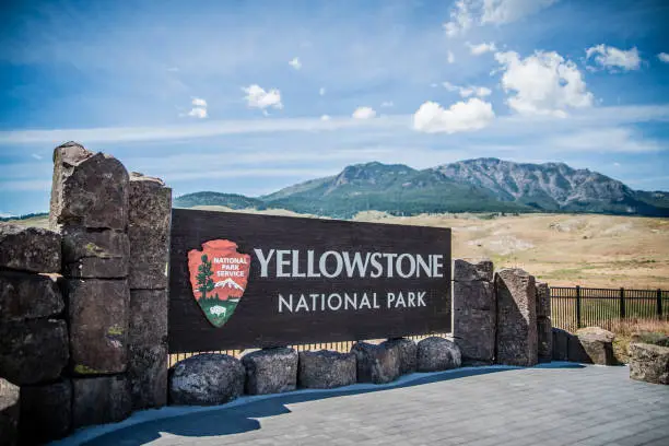 Yellowstone National Park sign with a desert and mountain in the background.